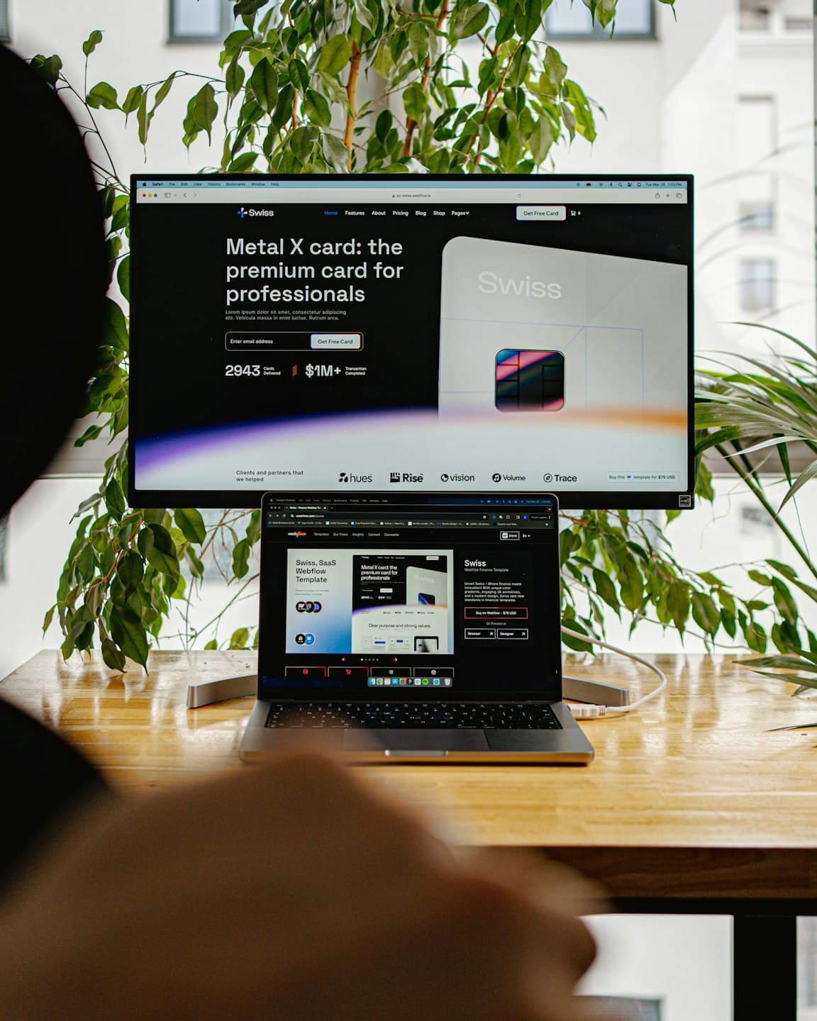 Diseñador trabaja en un portátil y monitor con diseño web.