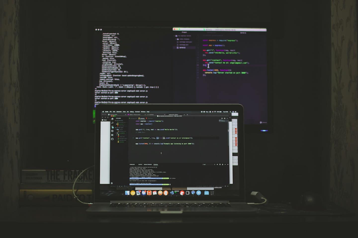 Portátil y monitor externo mostrando código en un escritorio.