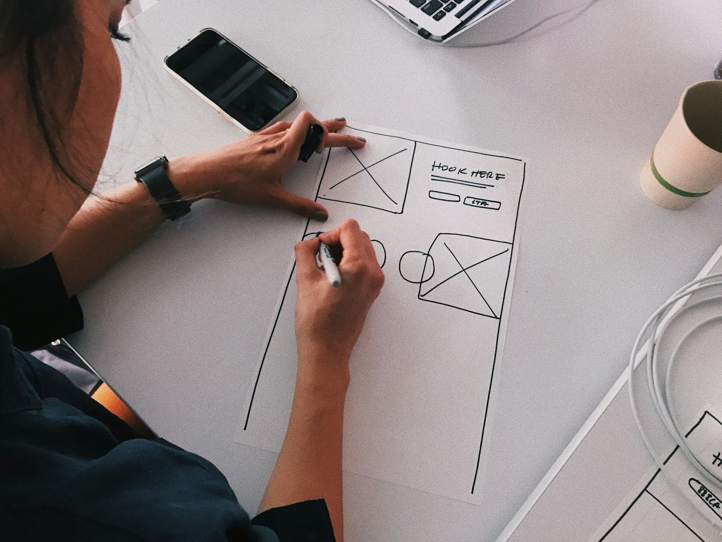 Diseñador esbozando wireframe de sitio web con etiquetas sobre el escritorio.