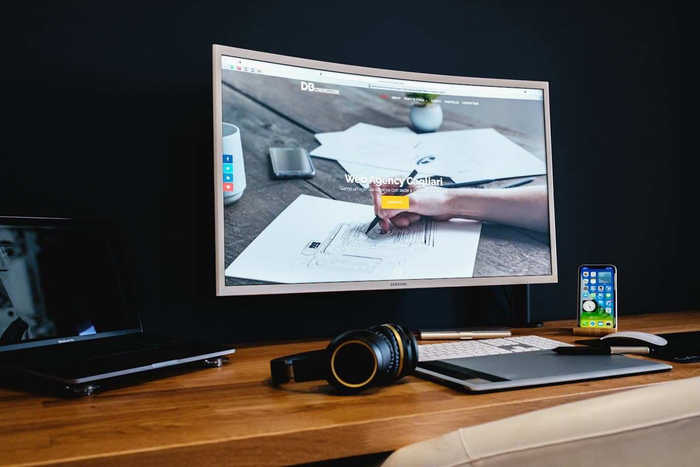 Escritorio de diseñador con monitor curvo, portátil y tableta gráfica.